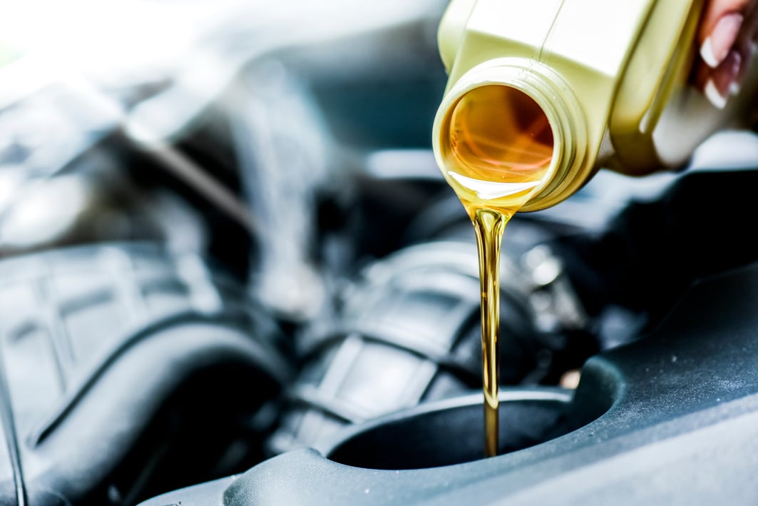 Woman hand pour motor oil to car engine.